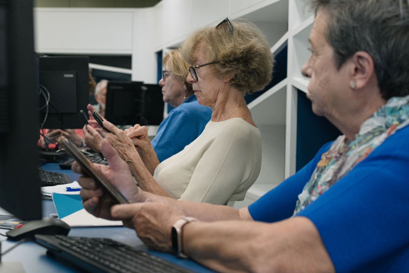 Un grupo de personas mayores sigue las explicaciones de una docente en sus teléfonos móviles Un grupo de personas mayores sigue las explicaciones de una docente en sus teléfonos móviles