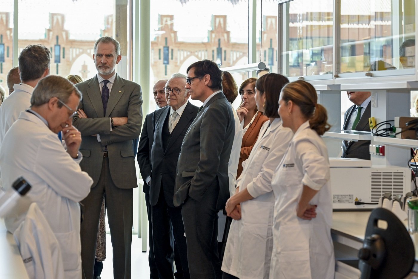 S. M. el Rey, Isidro Fainé y Salvador Illa escuchando a los investigadores del CaixaResearch Institute